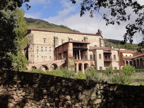 Um edifício histórico de pedra com várias abóbadas e um pátio central.