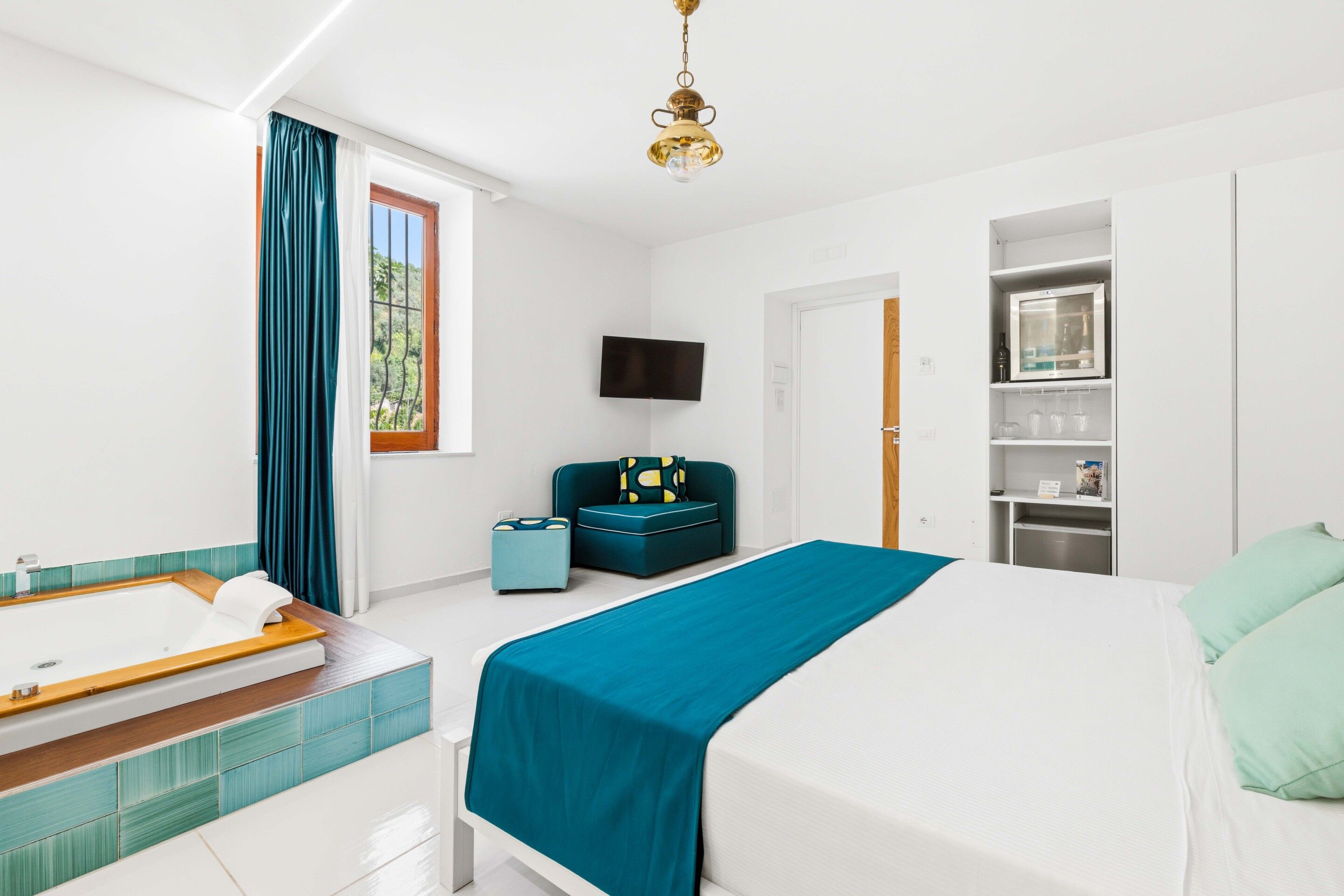 A modern hotel room with a bed, a bathroom, a TV, and a wardrobe.