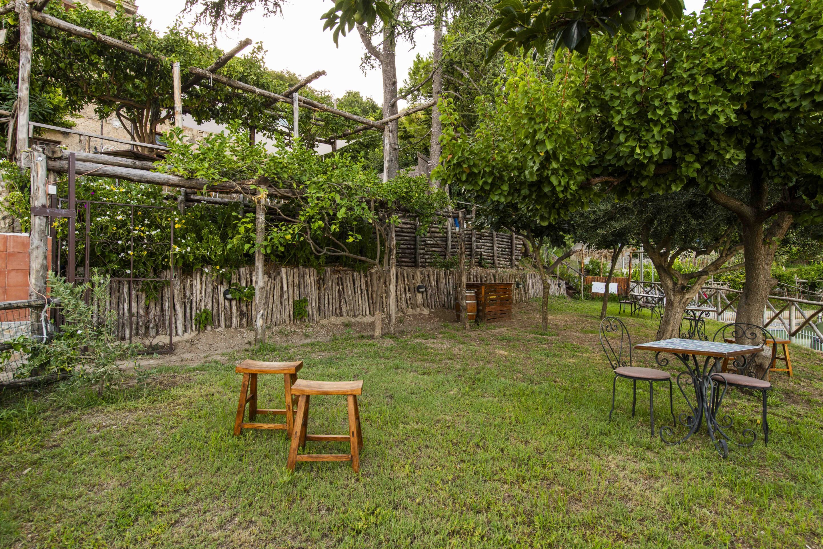 An outdoor area with a wooden table and chairs, a metal table, and a wooden bench.