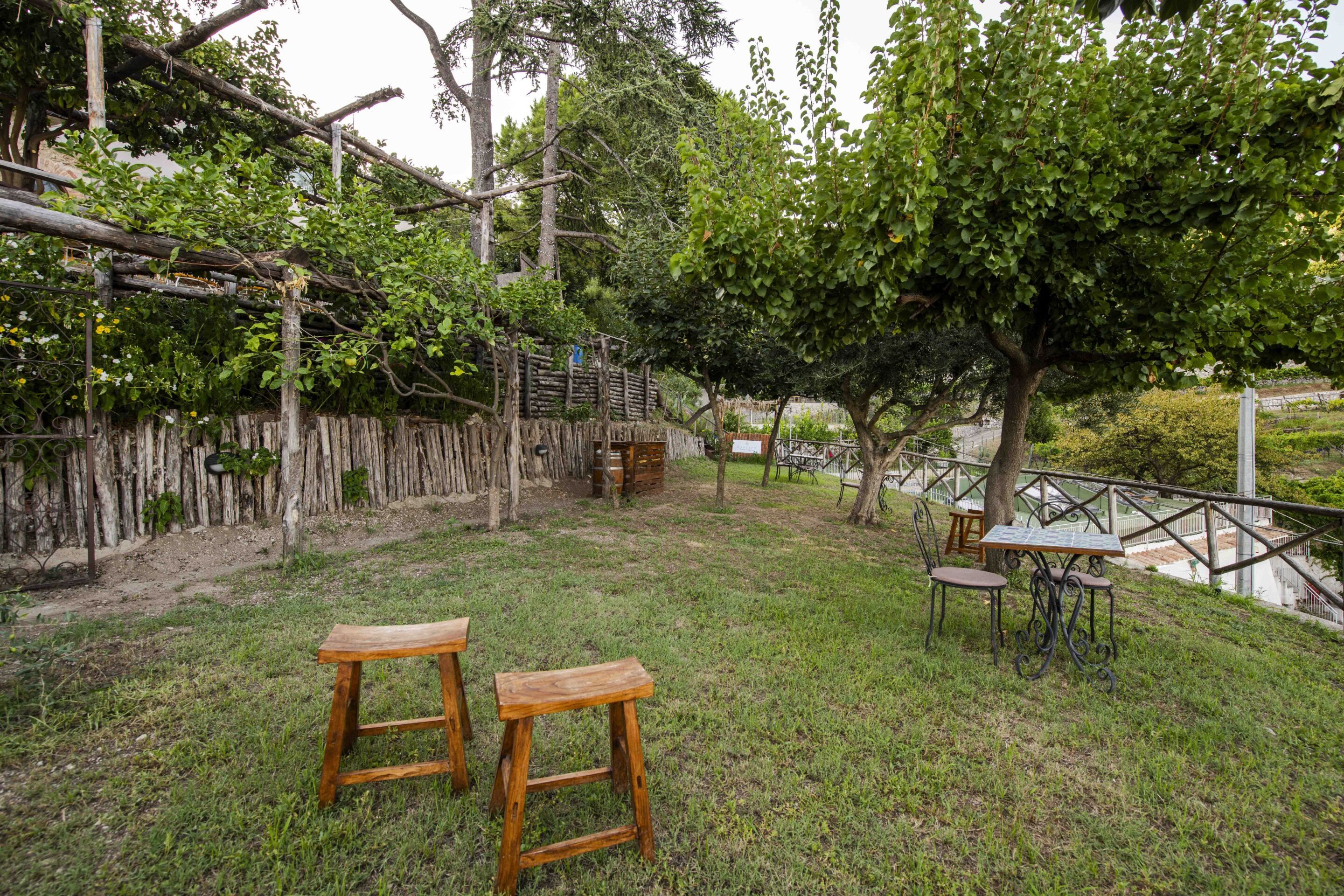 Un espacio al aire libre con césped, bancos de madera, una mesa y sillas.