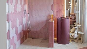 A modern bathroom with a shower area, a vanity with a mirror, and a seating area with a table and chairs.