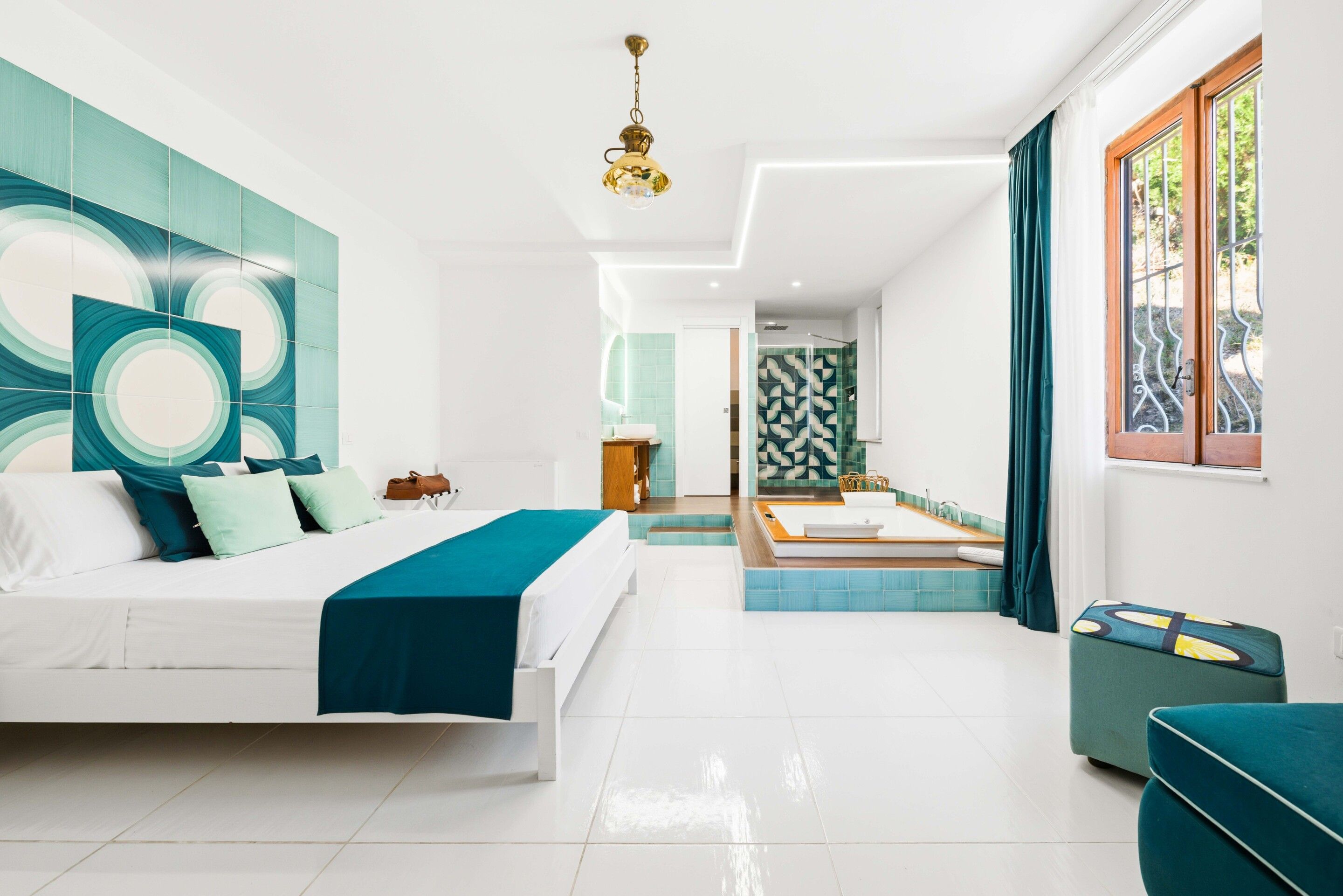 Une chambre moderne avec un grand lit, une salle de bain avec baignoire et une vue sur l’extérieur.