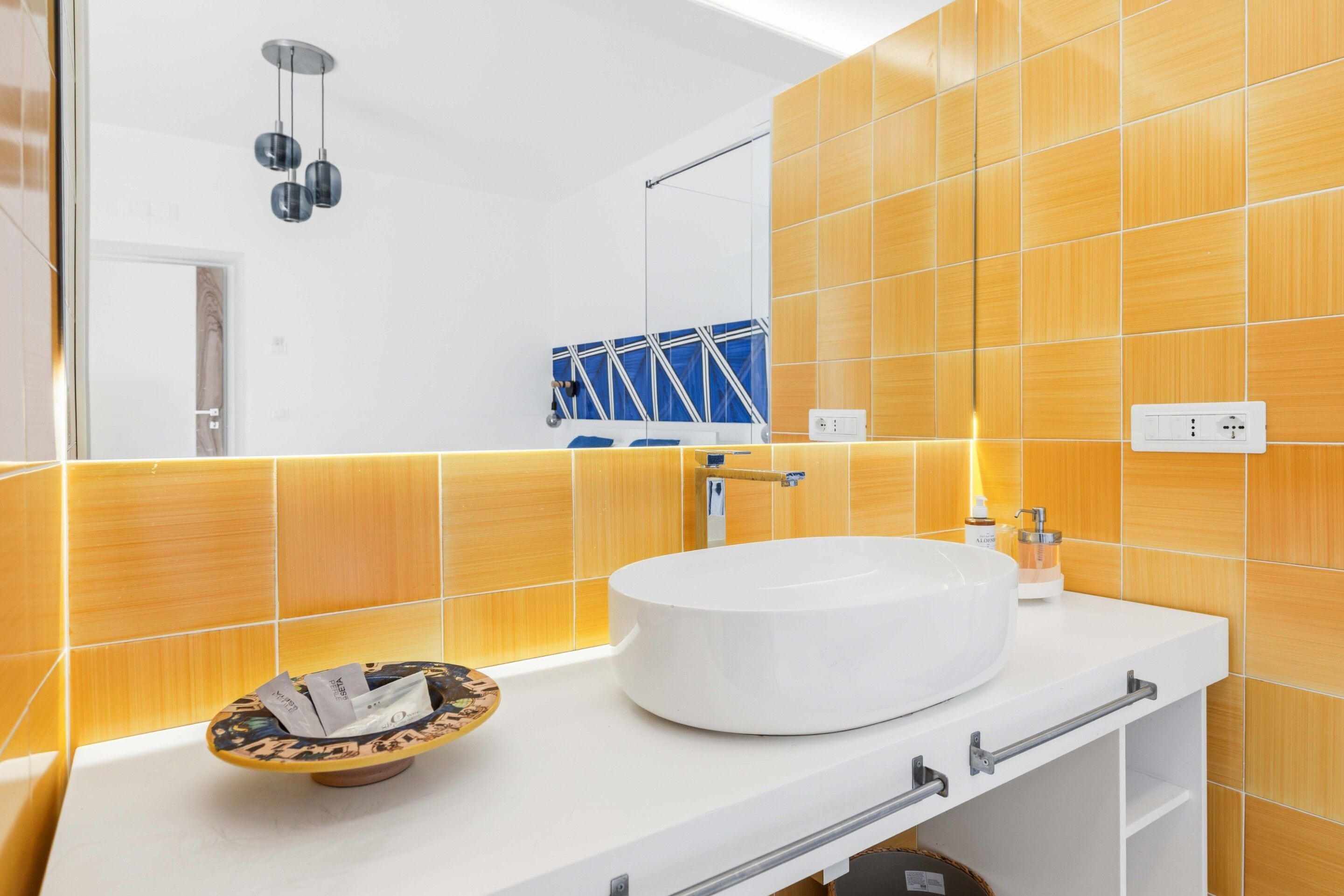 Un baño moderno con un lavabo blanco, un espejo y un perchero para toallas.