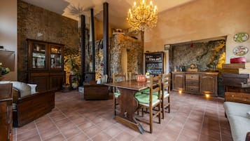 A rustic interior with a dining table, chairs, a chandelier, and stone walls.