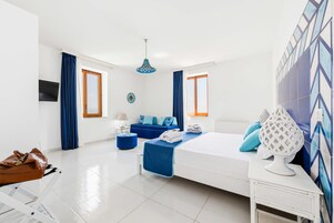 Habitación de hotel moderna con cama, sofá, lámpara y un adorno en la pared.