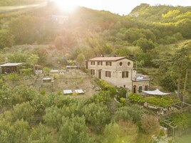 A hillside villa with a stone facade, multiple windows, and a flat roof.
