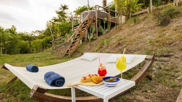 A hammock with a picnic setup including food, drinks, and towels.