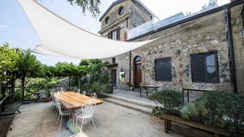 Un edificio rústico de piedra con una mesa y sillas de madera en el patio.