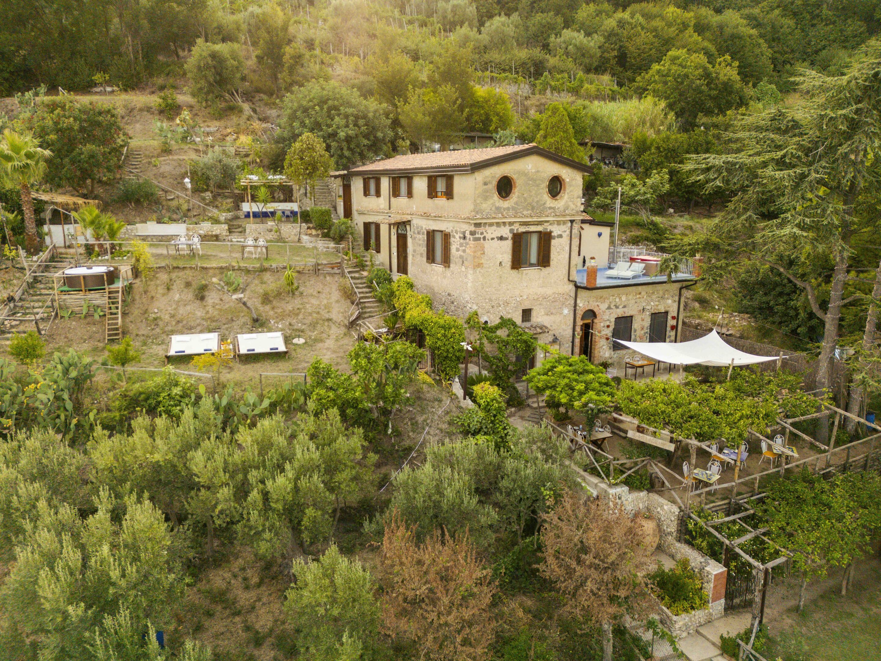 A stone building with a flat roof, surrounded by trees and a garden.