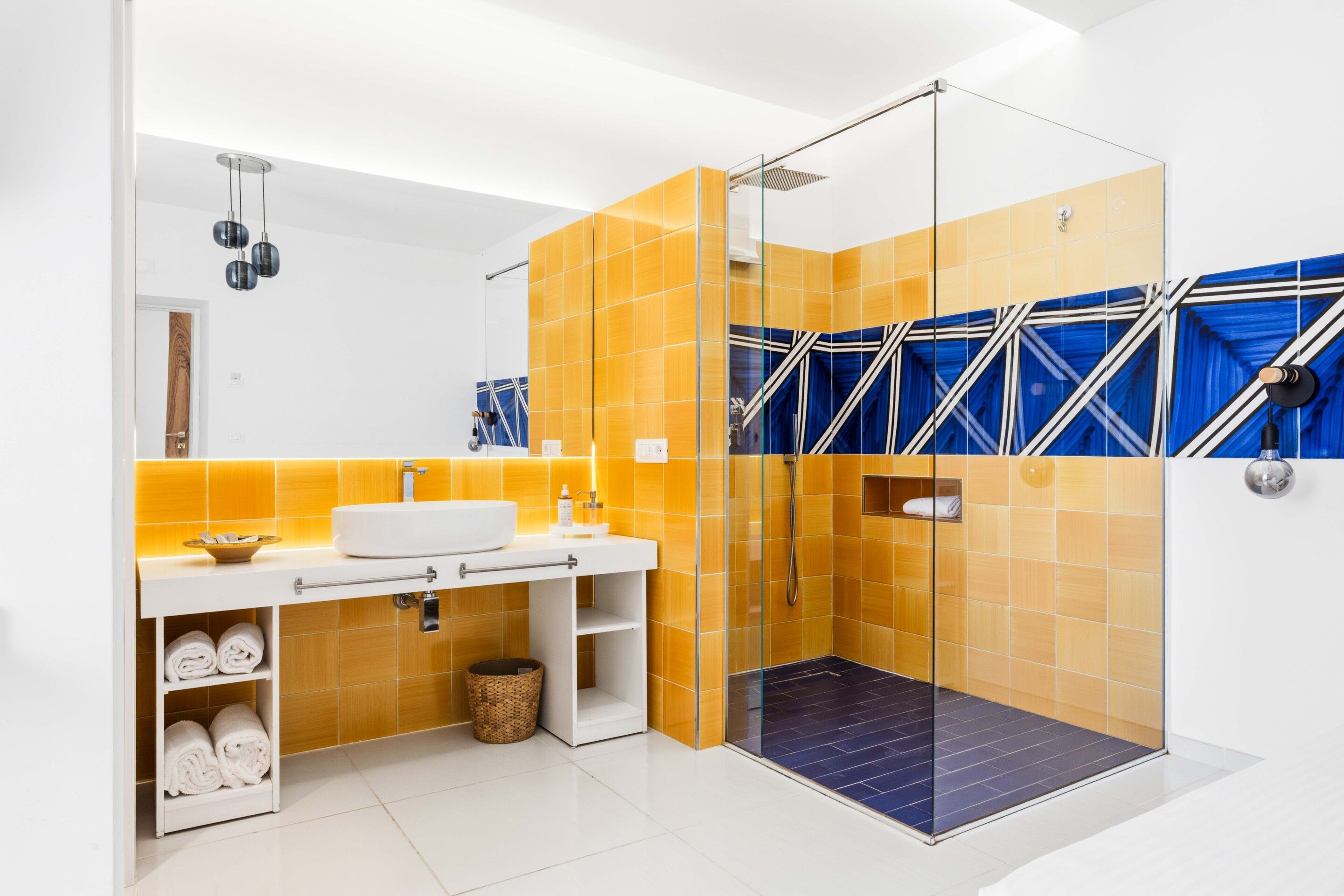 Un baño moderno con cabina de ducha de vidrio, un lavabo blanco y un perchero para toallas.