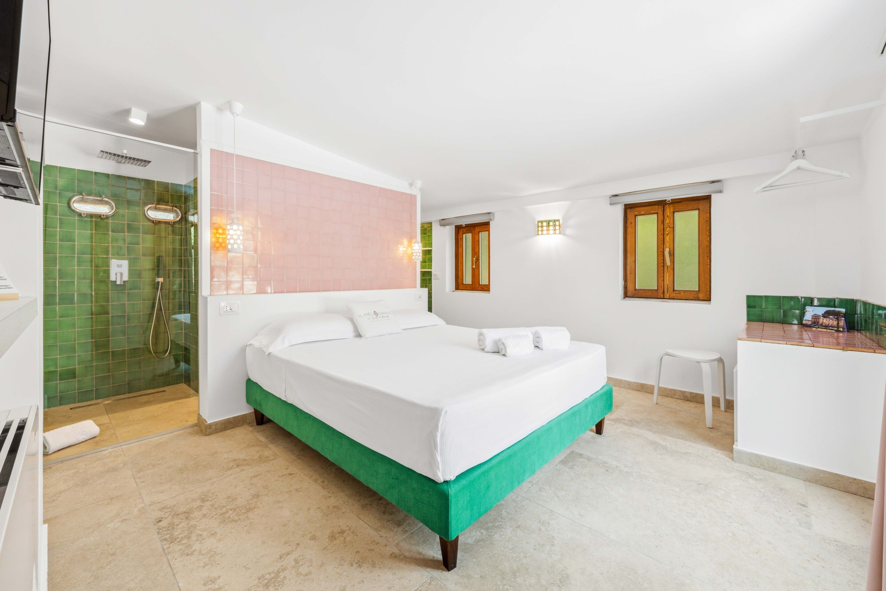 A hotel room with a bed, a shower, a small desk, and a window.
