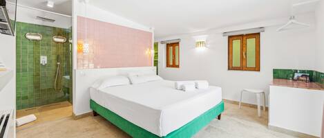 Una habitación de hotel con cama, ducha, escritorio pequeño y ventana.