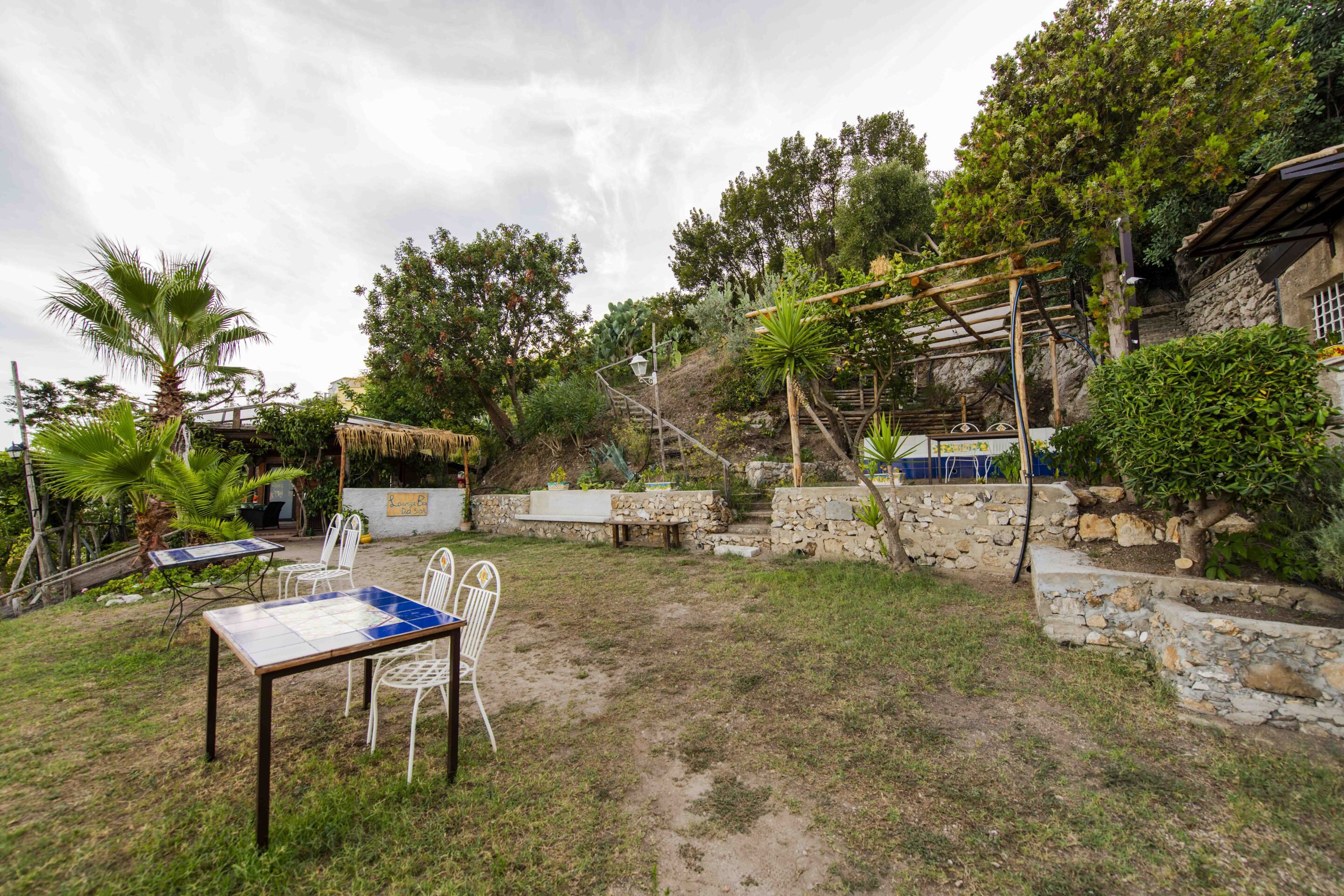 Un espace patio aménagé avec une table et des chaises, entouré de murs en pierre et de végétation.