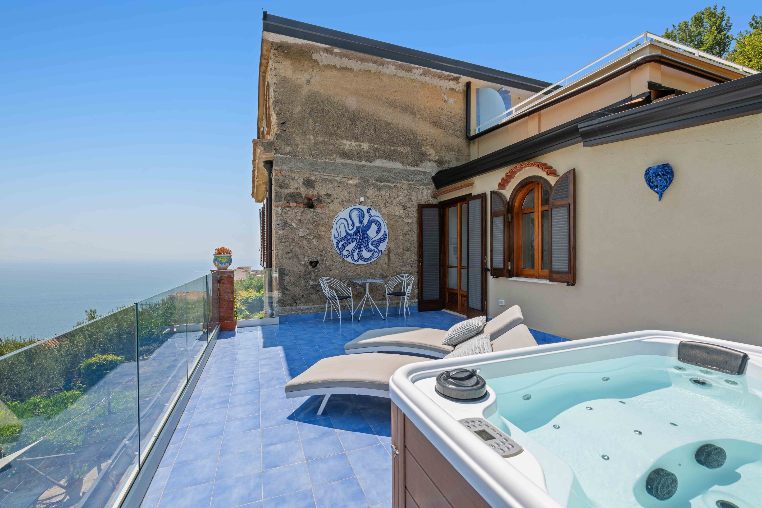 Une terrasse sur le toit avec un jacuzzi, des sièges extérieurs et une vue sur la mer.