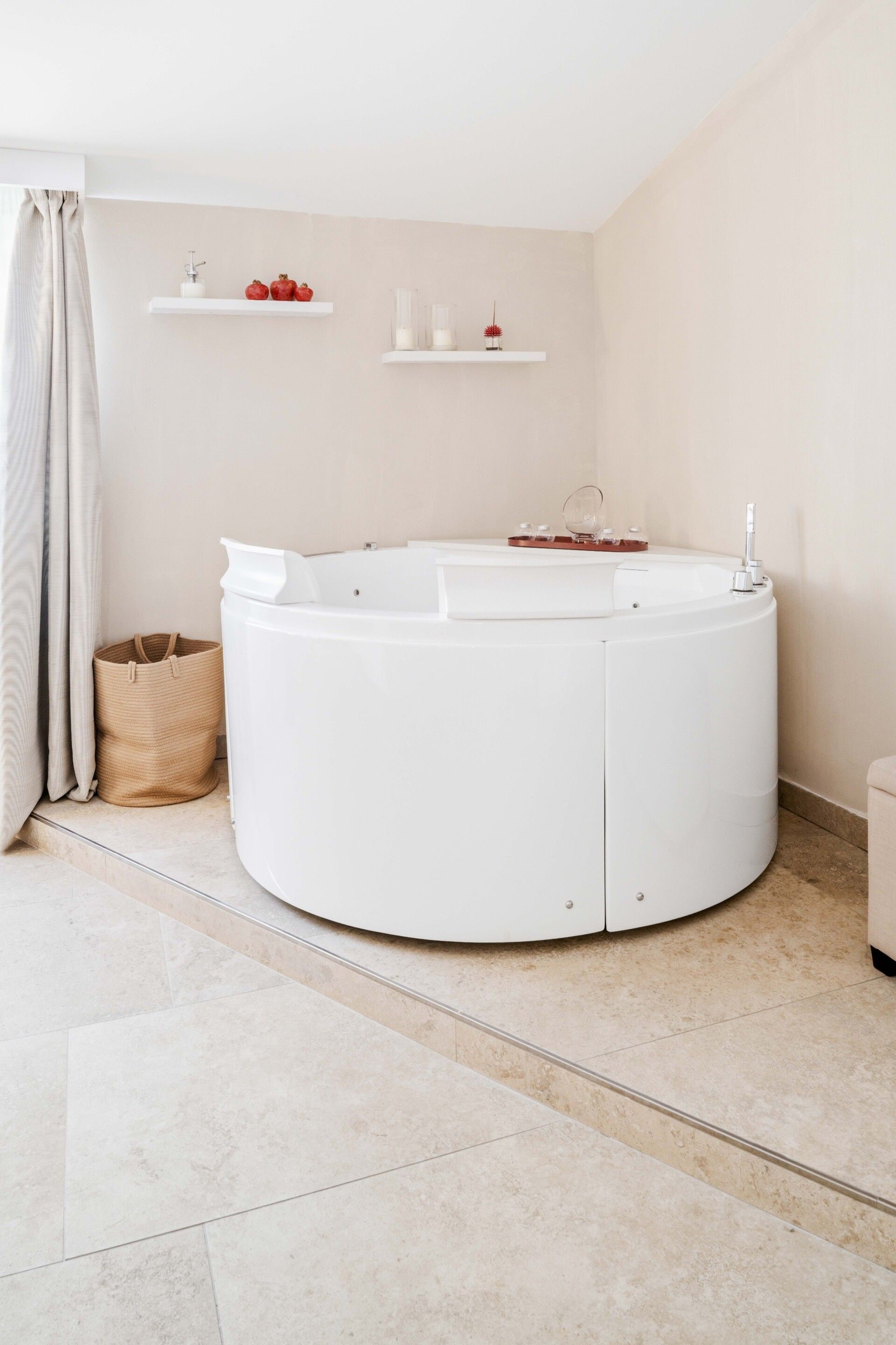A modern bathroom with a freestanding bathtub, a towel rack, and a small shelf with decorative items.
