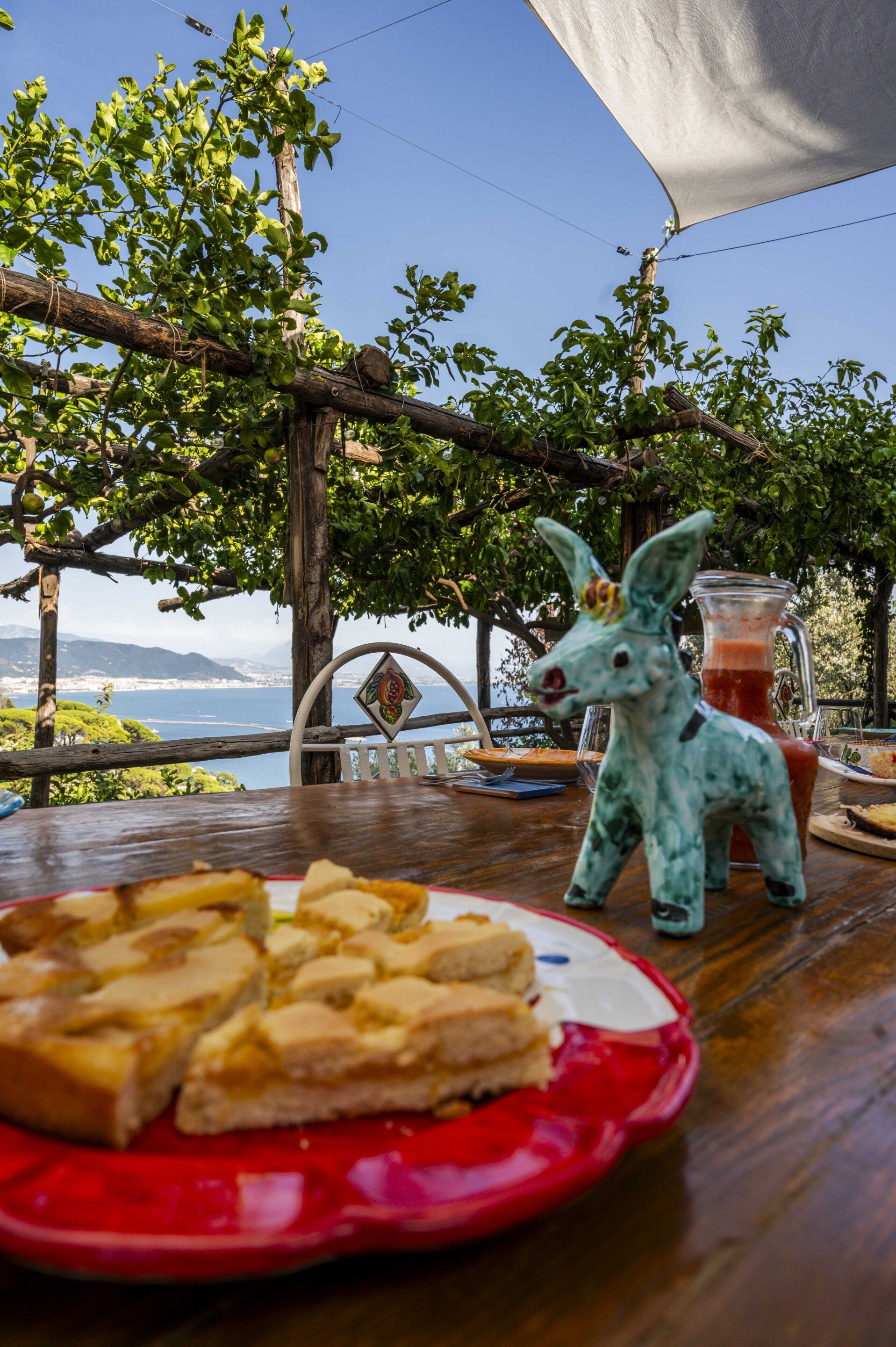 A table with a plate of food, a glass pitcher, and a decorative donkey figurine.