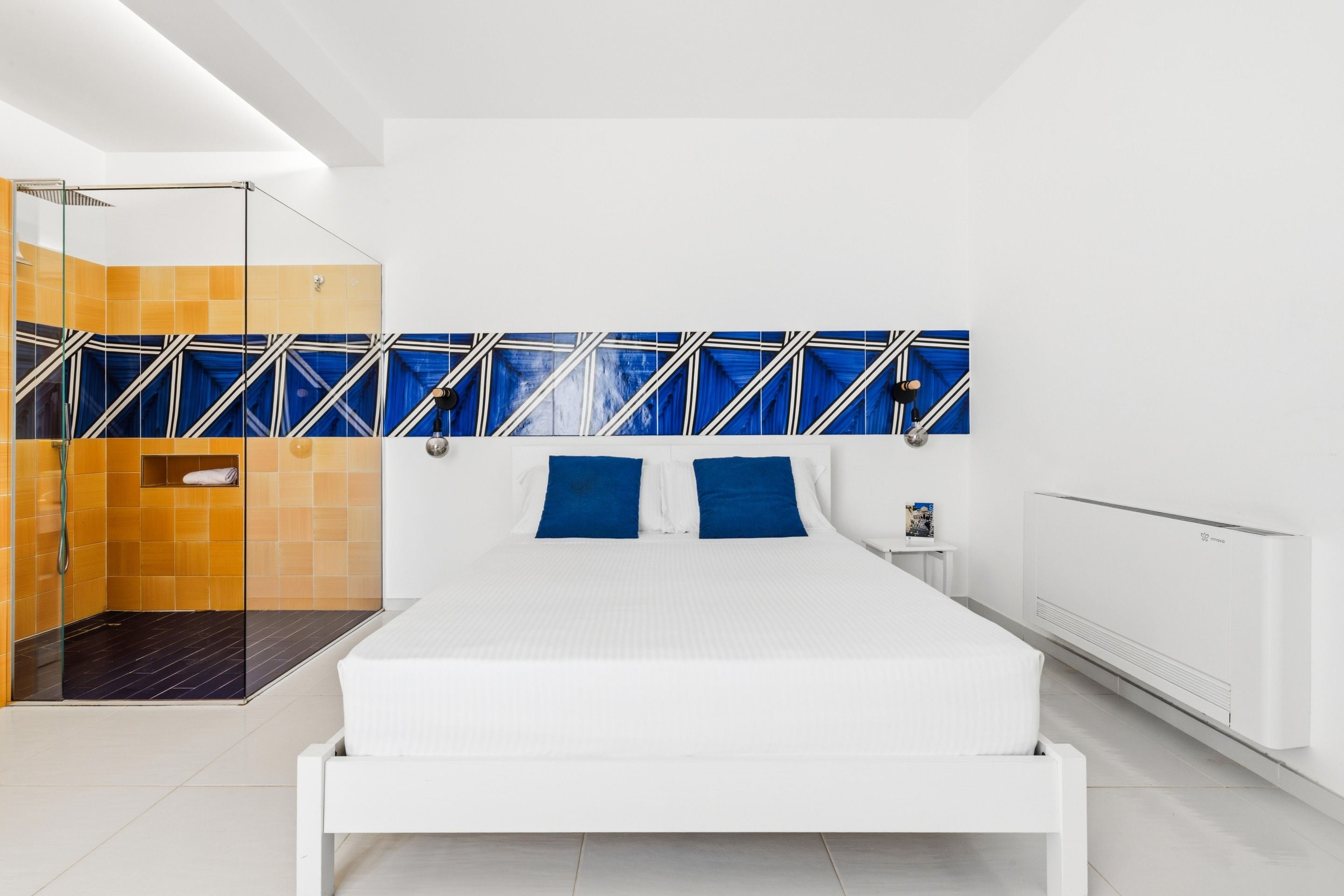A modern bedroom with a large bed, a glass shower enclosure, and a white radiator.