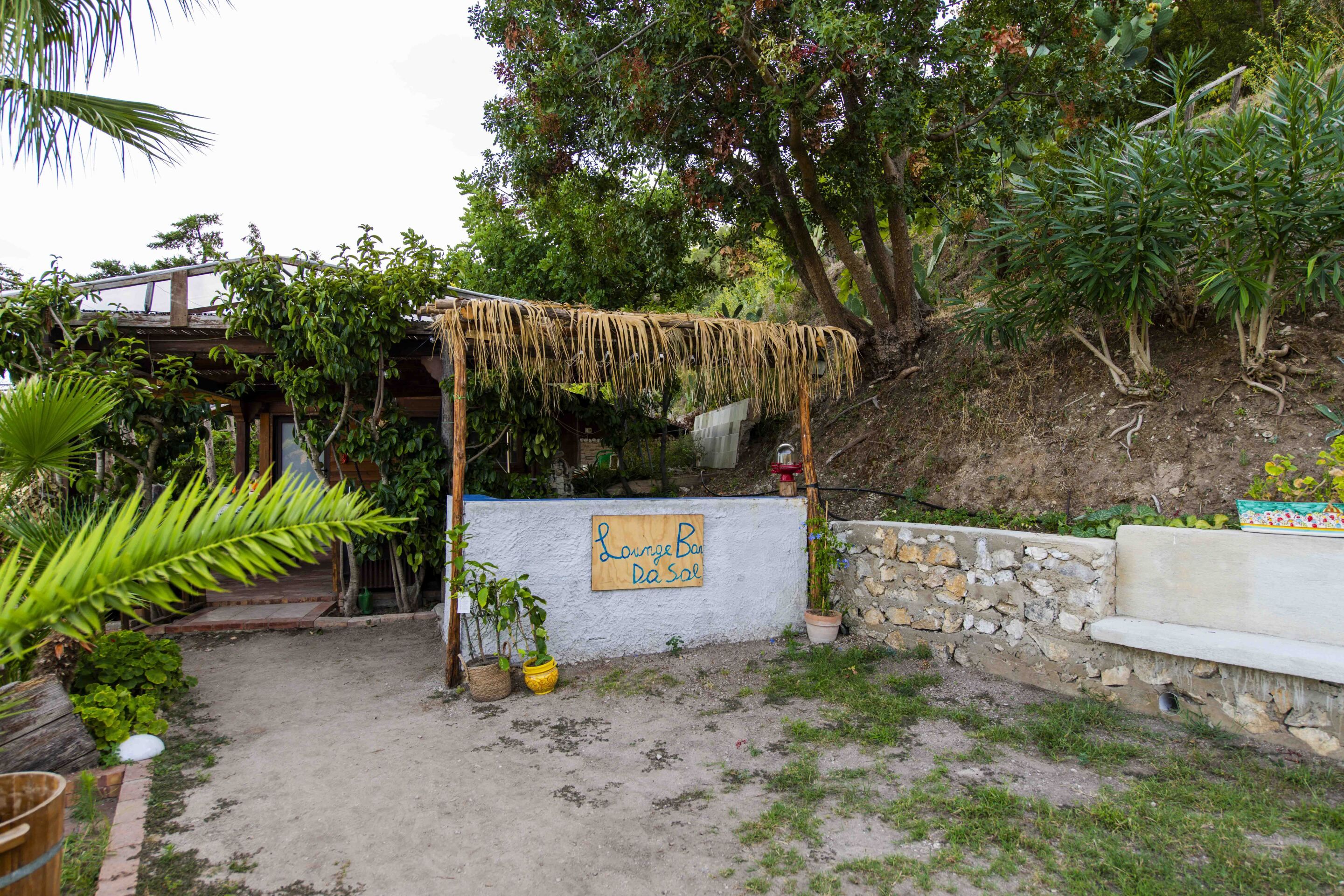 Un espacio de estar al aire libre de estilo rústico, con una estructura de madera y un cartel que dice 'Lounge Bar Da Sal'.
