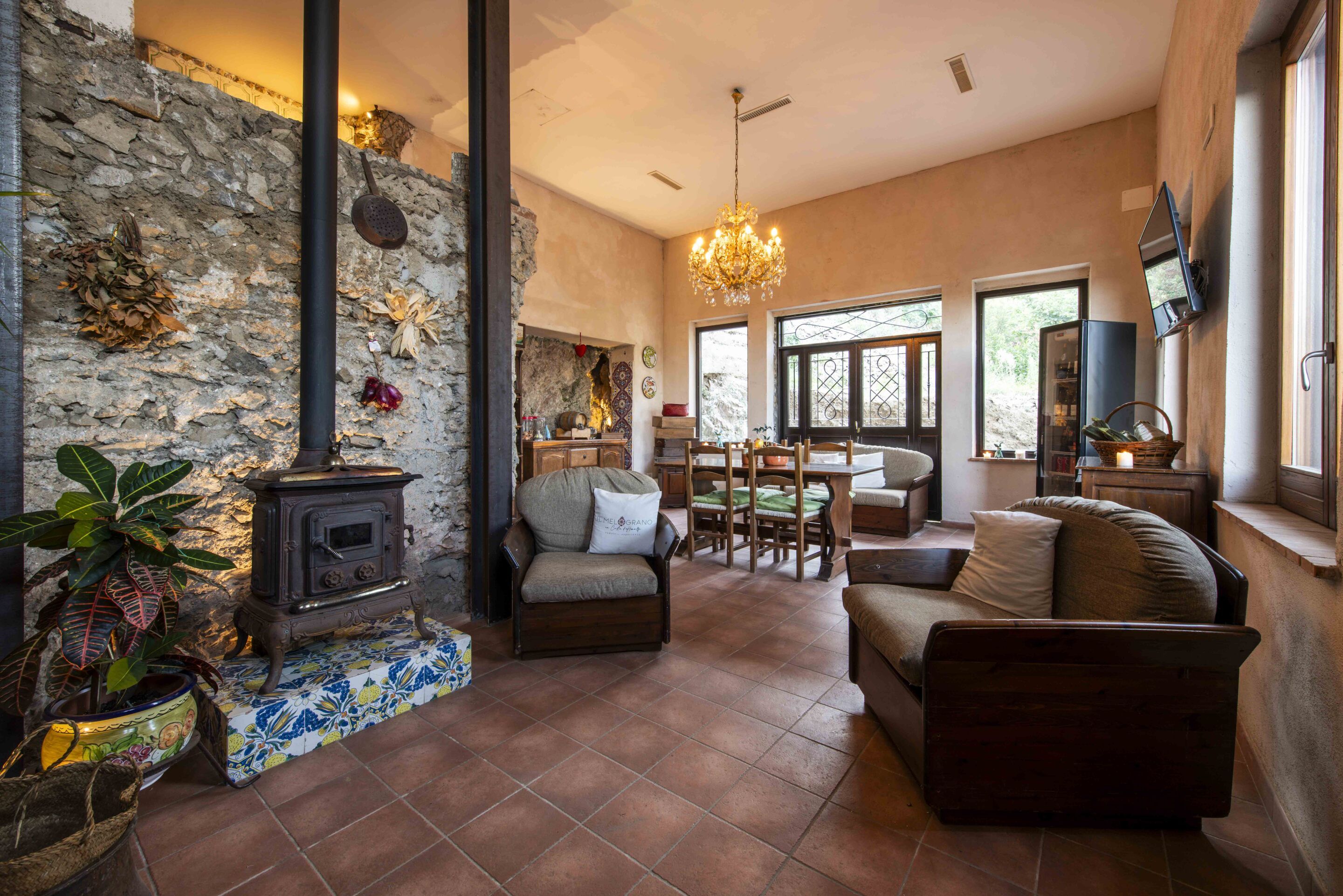 A cozy living room with a stone wall, a fireplace, and a chandelier.