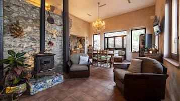 A cozy living room with a stone wall, a fireplace, and a chandelier.