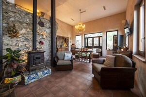 Una sala de estar acogedora con una pared de piedra, una chimenea y un candelabro.