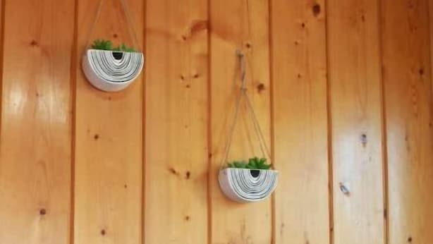 A wooden wall with two hanging planters and a table with two white mugs and a sign that reads "Sip & Repeat". - Cozy little cottage in the heart of the Gem City (Quincy)