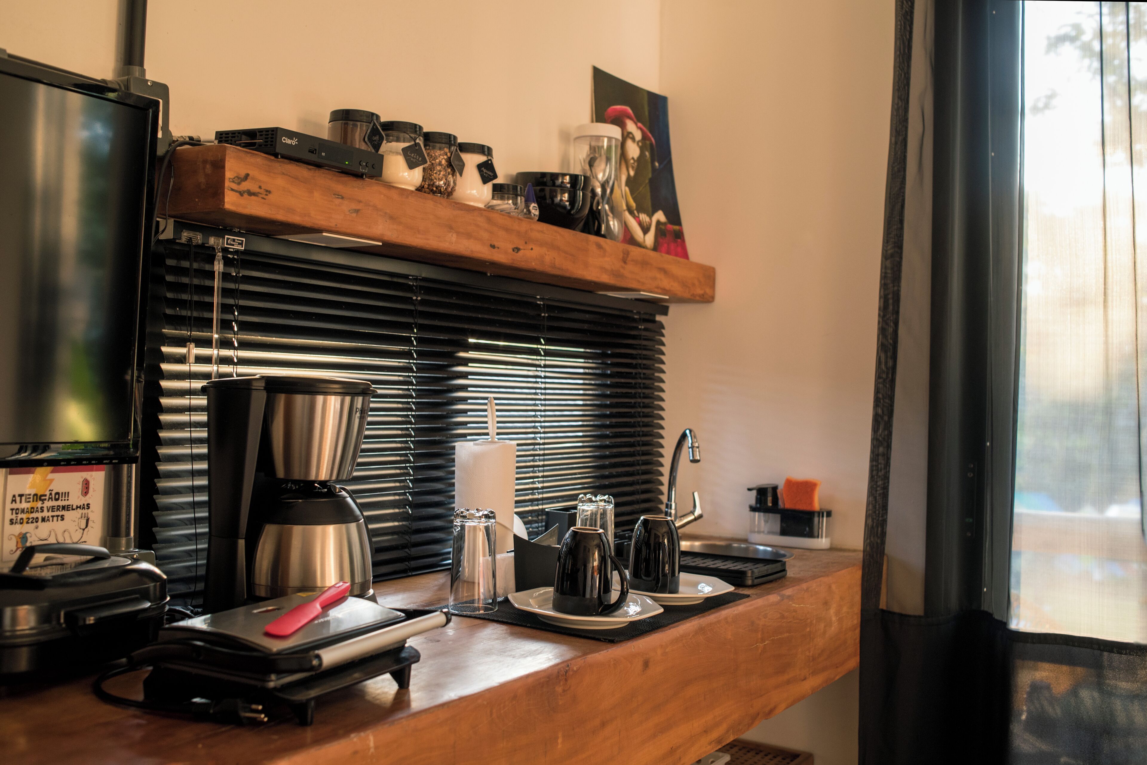 A kitchenette with a coffee maker, a toaster, and a kettle on the counter.