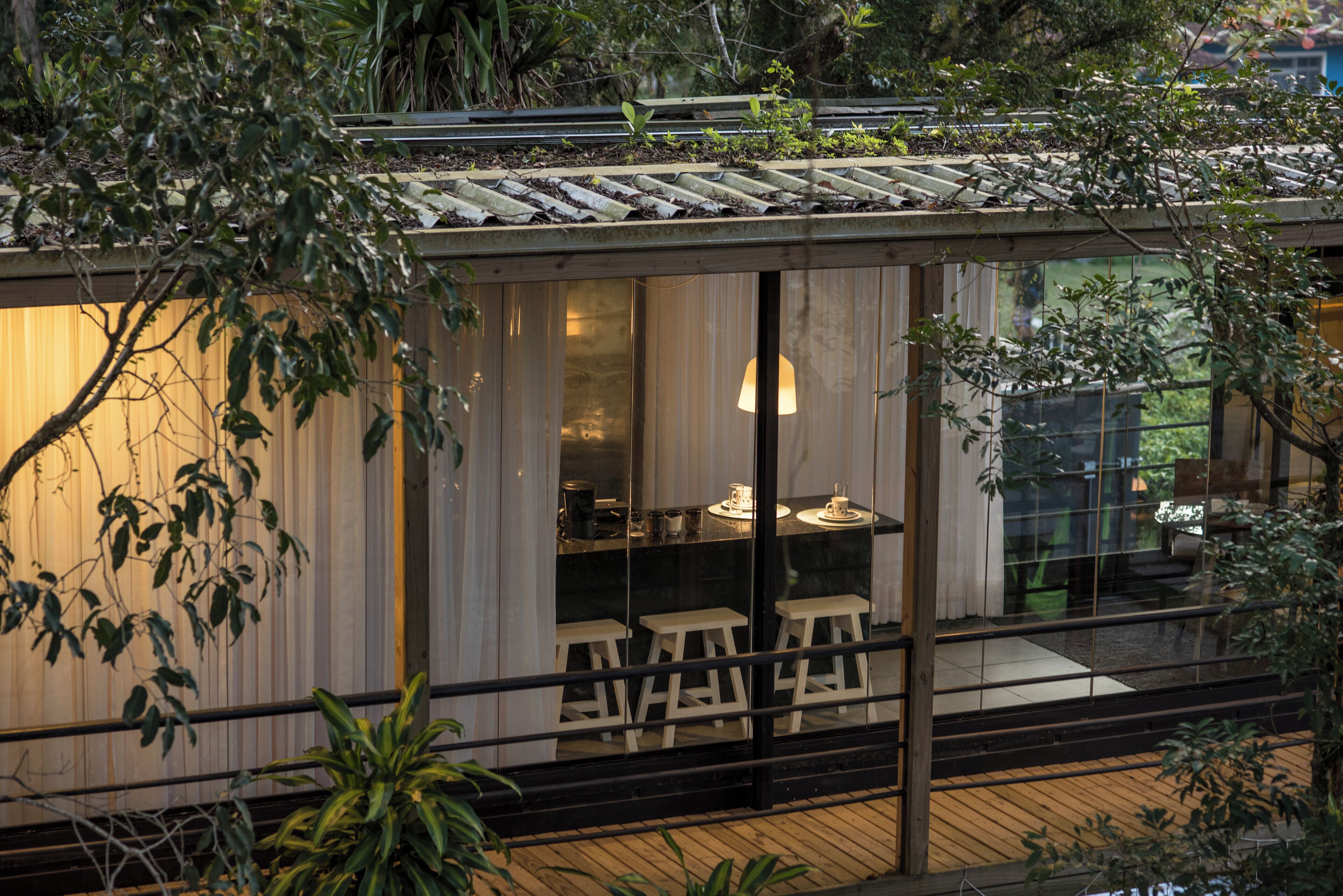 A modern house with a dining area, wooden deck, and large windows.
