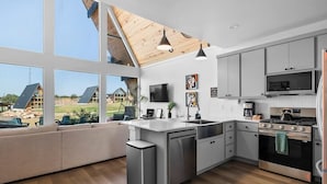 Una cocina moderna con una isla grande, electrodomésticos de acero inoxidable y vistas al exterior.