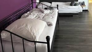 A hotel room with two beds, a purple wall, and a wooden floor. - Apartment 1880 (Werne)