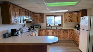 Una cocina con armarios de madera, una isla central, un microondas, un refrigerador y un ventanal que proporciona luz natural.
