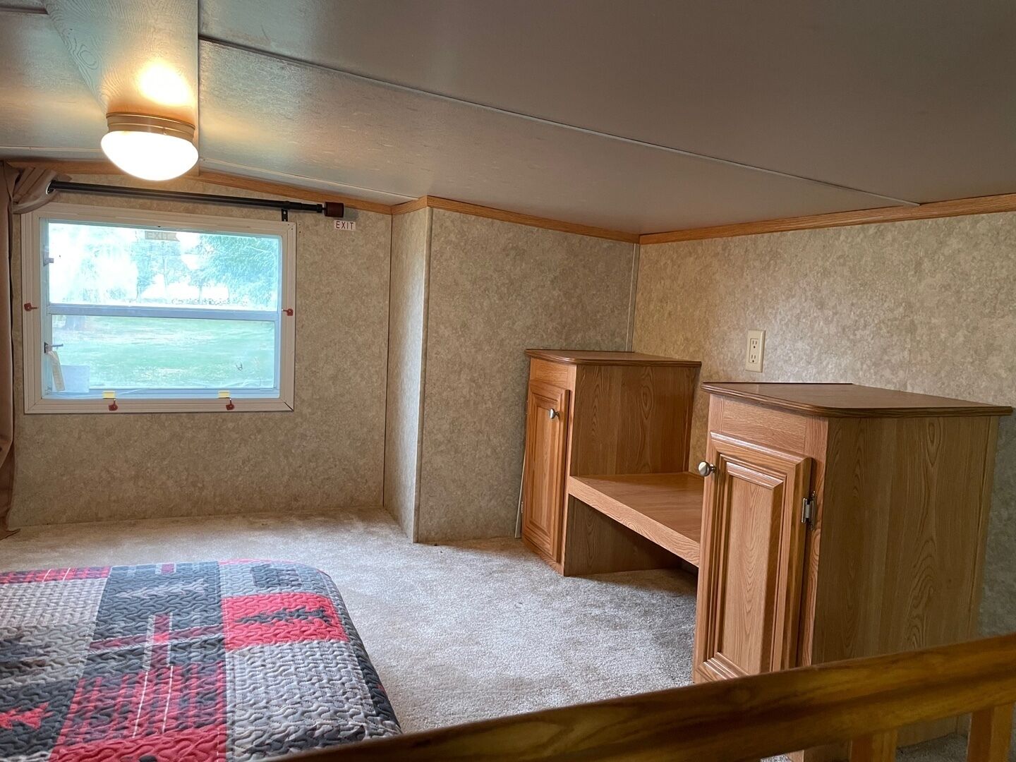A bedroom with a window, a bed, a nightstand, and a wooden cabinet.