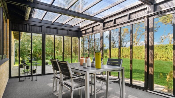 A conservatory with a glass roof, a dining table with chairs, and a view of a garden. - Awesome home in Nykøbing M (Nykøbing M)