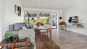 A living room with a grey sofa, a wooden coffee table, a wicker chair, and a TV on a shelf. - Awesome home in Nykøbing M (Nykøbing M)