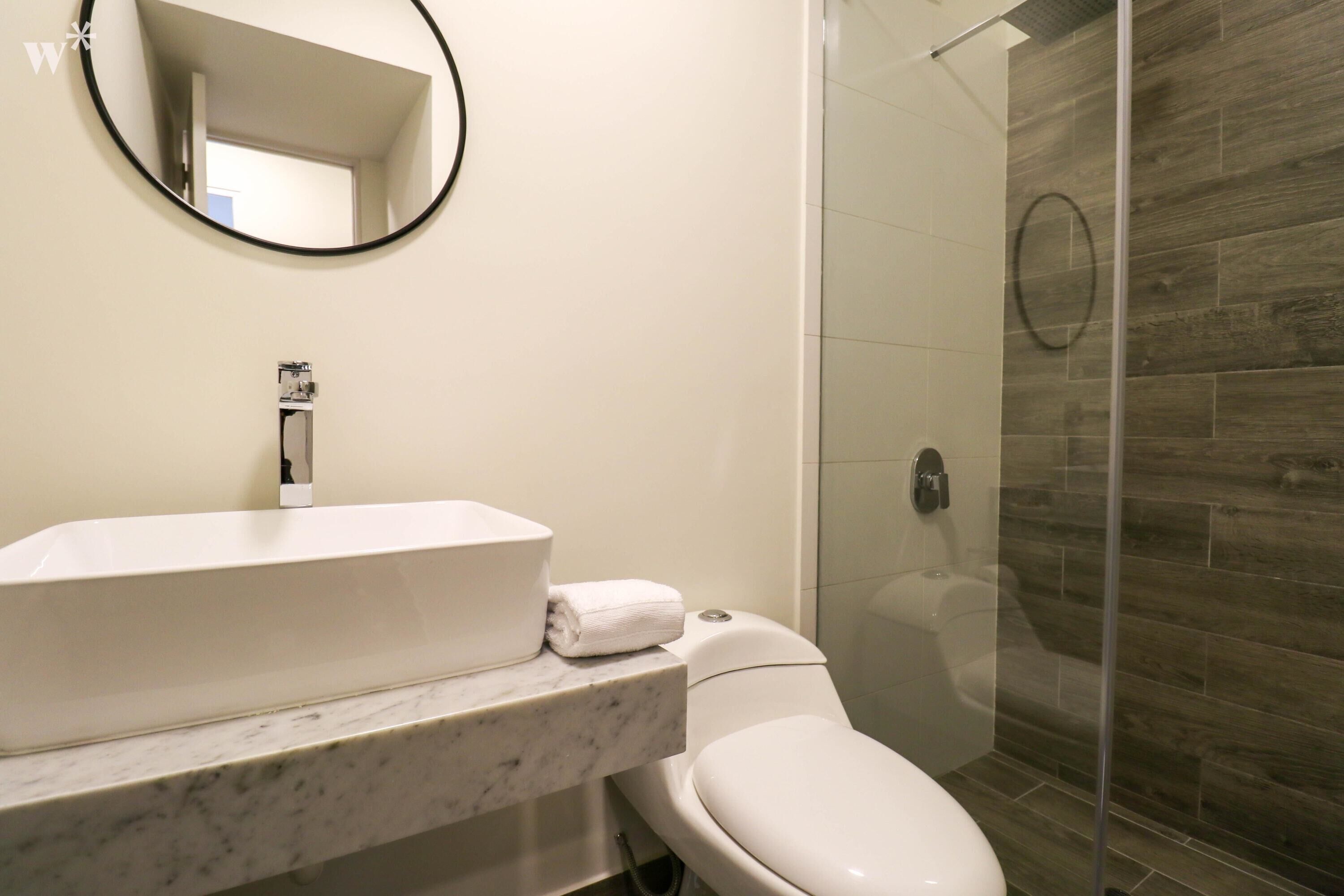 Un bagno con un lavabo in marmo, un water e una cabina doccia in vetro.