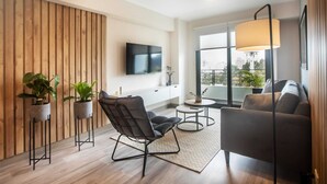 A modern living room with a wooden accent wall, a flat-screen TV, a sofa, a chair, and potted plants. - Wynwood The Classic in San Isidro (Lima)