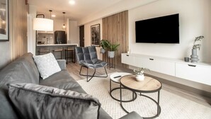 A modern living room with a grey sofa, a round coffee table, and a TV mounted on the wall. - Wynwood The Classic in San Isidro (Lima)