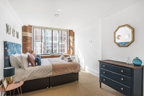 Enjoy a city view from the large window, with a comfortable bed, bedside table, and dresser.
