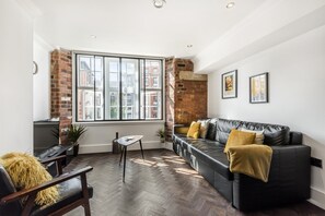 Relax in a stylish living room with a city view, featuring a comfortable sofa, side table, and potted plant.