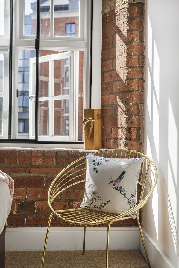 Enjoy the view of the city from this corner room, featuring a large window and a stylish chair with a unique cushion.