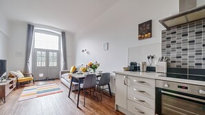 A modern kitchen with a built-in oven, a dining area with a table and chairs, and a large window with curtains. - County House Escape - courtyard & free parking (York)