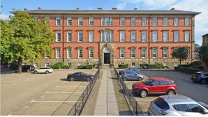 A large, red-brick building with a symmetrical facade, multiple windows, and a central entrance. - County House Escape - courtyard & free parking (York)