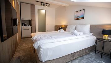 Ein modernes Hotelzimmer mit einem großen Bett, einem Nachttisch, einem Schreibtisch und Blick zum Himmel durch ein Oberlicht.