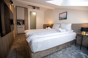 Habitación de hotel moderna con una cama grande, una mesita de noche, un escritorio y vistas al cielo a través de un tragaluz.