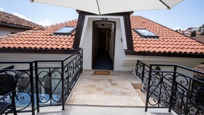 A balcony with a tiled roof, a door leading to an interior space, and a metal railing. - Villa Pupin SARAISTE (Ohrid)
