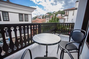 Un balcón con una mesa redonda y dos sillas, con vista a una zona residencial con casas y una iglesia.