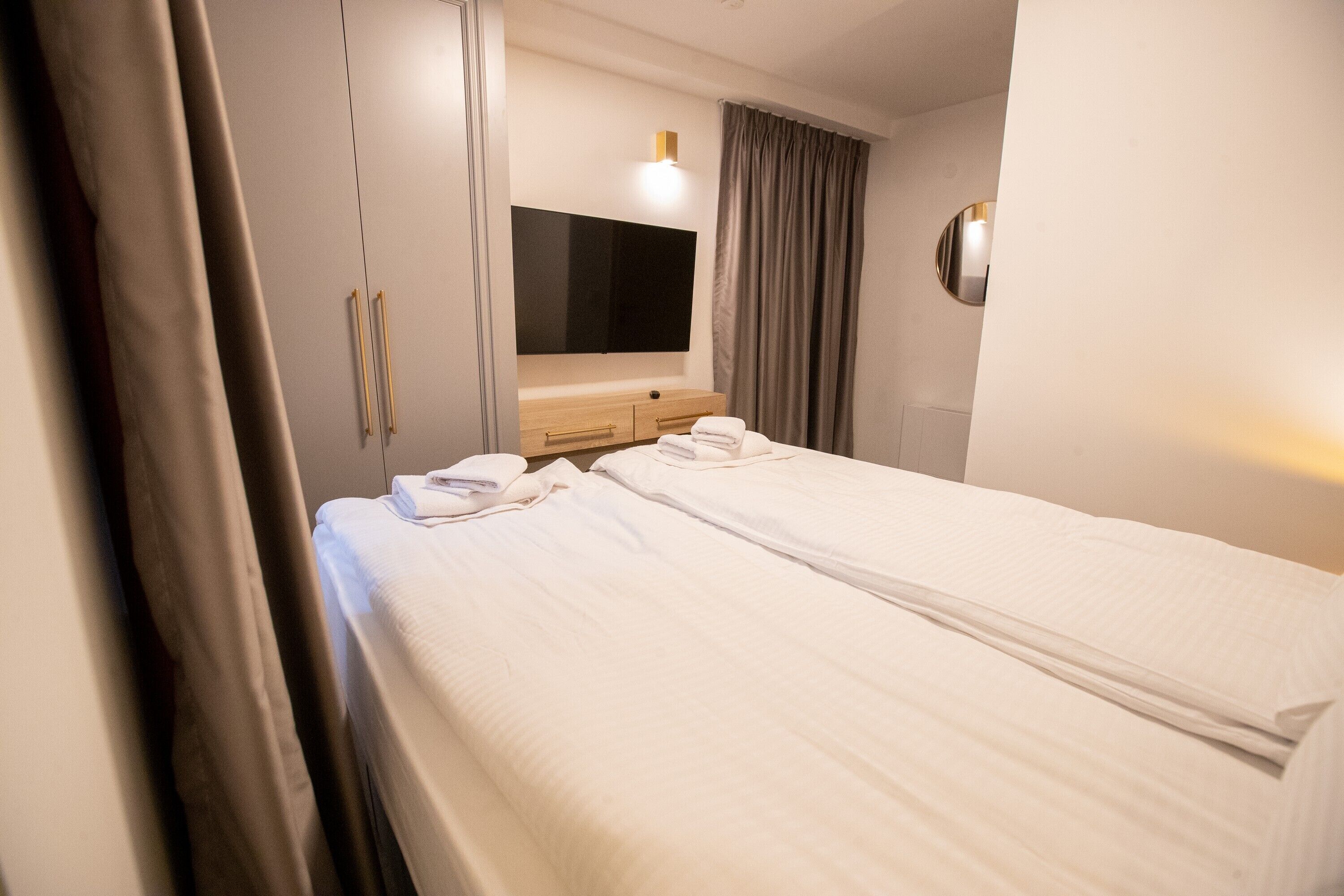 A hotel room with two beds, a TV, a wooden dresser, and a large mirror.