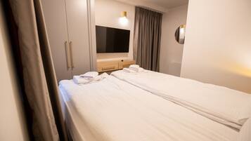 A hotel room with two beds, a TV, a wooden dresser, and a large mirror.