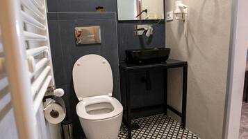 Un baño con inodoro, lavamanos y espejo.