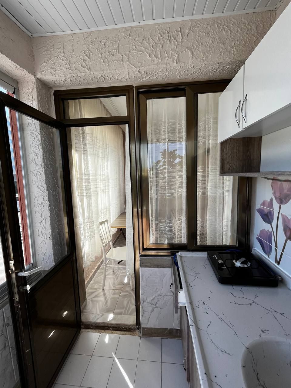 Een moderne keuken met een marmeren aanrechtblad, een inbouwoven en uitzicht op het balkon.